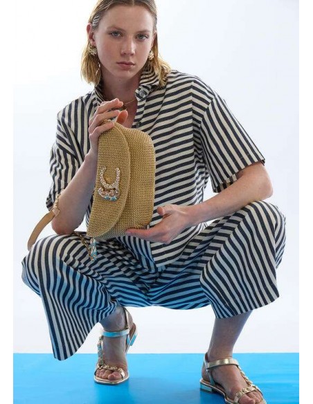 Bolso trenzado con solapa y cadena LC de LOLA CASADEMUNT - modelo agachada sujeta el bolso beige en las manos.