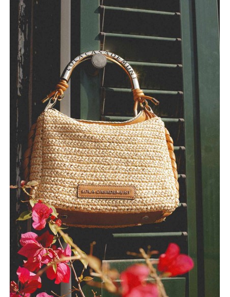 Bolso bandolera efecto rafia asa troquelada con logo · Lola Casademunt - bolso en el exterior colgado.