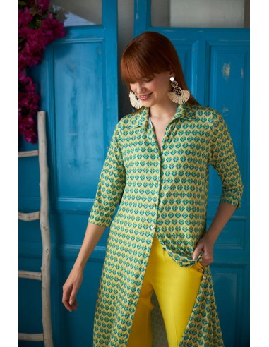 Modelo con el vestido Reiko verde combinado con un pantalón amarillo en una habitación con puertas azules.