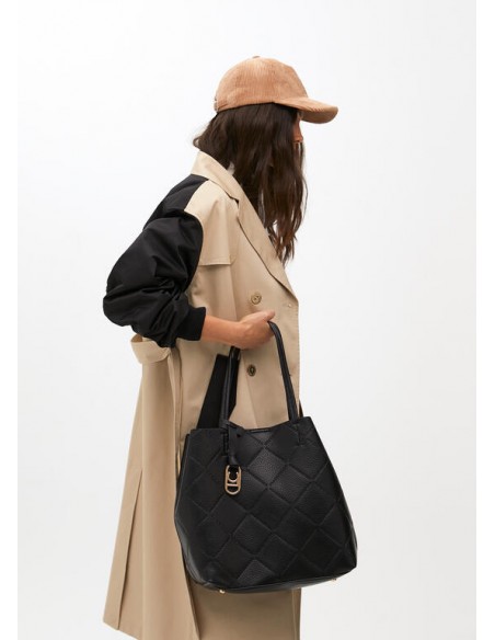 Modelo lleva en la mano el bolso shopper negro efecto piel con logo LC de Lola Casademunt Modelo lleva en la mano el bolso shopper negro efecto piel con logo LC de Lola Casademunt