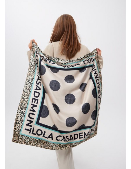 Pañuelo Lola Casademunt con Topos y Logo Animal Print - modelo sostiene el pañuelo abierto en su espalda.